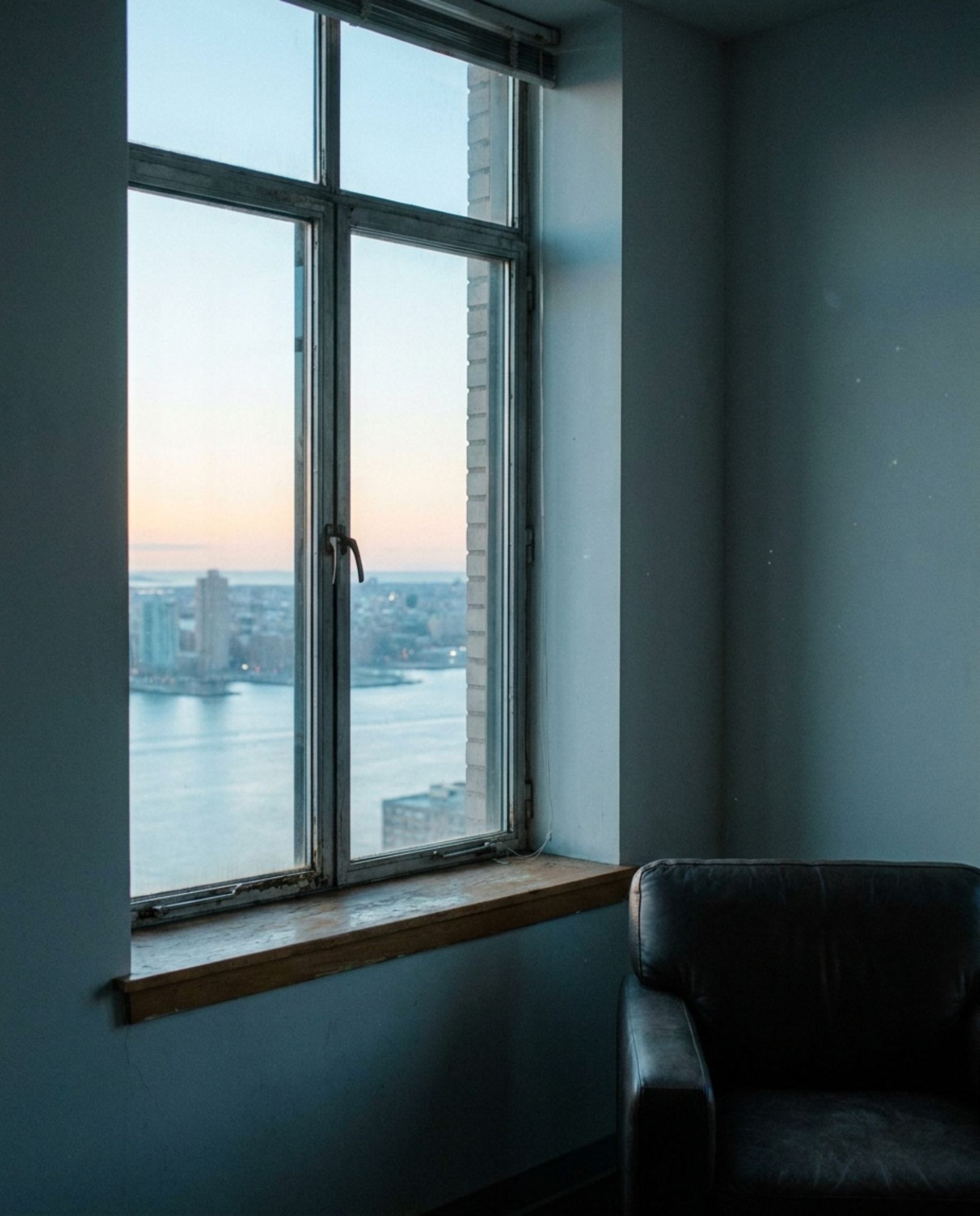 An office window high above Manhattan looking east over the river at dawn